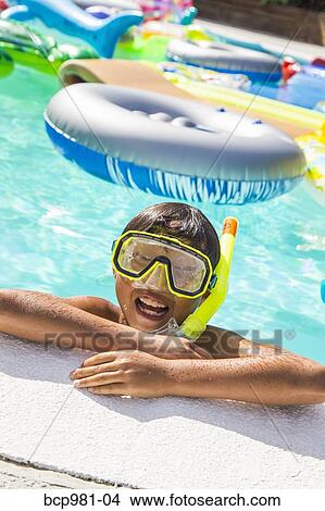 Boy wearing a scuba mask and snorkel swims in a pool full of inflatable toys View Large Photo Image Picture - Boy wearing a scuba mask and snorkel swims in a pool full of inflatable toys. Fotosearch