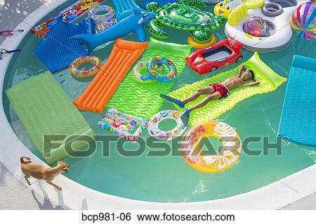 Boy wearing flippers floats in a pool full of inflatable toys View Large Photo Image Stock Photograph - Boy wearing flippers floats in a pool full of inflatable toys. Fotosearch