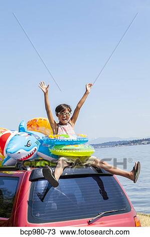 Child poses beach toys and floaties on the roof of a car View Large Photo Image Stock Image - Child poses beach toys and floaties on the roof of a car. Fotosearch