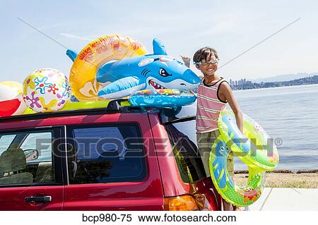 Child poses beach toys and floaties on the roof of a car View Large Photo Image Stock Photography - Child poses beach toys and floaties on the roof of a car. Fotosearch