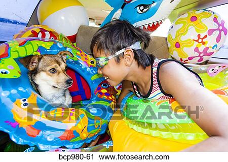 Stock Image - Child poses with his dog in a car full of beach toys and floaties. Fotosearch