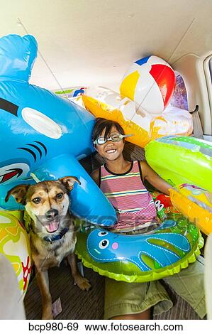 Child poses with his dog in a car full of beach toys and floaties View Large Photo Image Stock Photo - Child poses with his dog in a car full of beach toys and floaties. Fotosearch