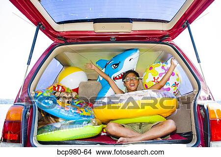 Child poses with his dog in the open trunk of a car full of beach toys and floaties View Large Photo Image Picture - Child poses with his dog in the open trunk of a car full of beach toys and floaties. Fotosearch
