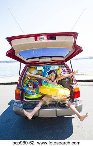 Child poses with his dog in the open trunk of a car full of beach toys and floaties View Large Photo Image Stock Image - Child poses with his dog in the open trunk of a car full of beach toys and floaties. Fotosearch