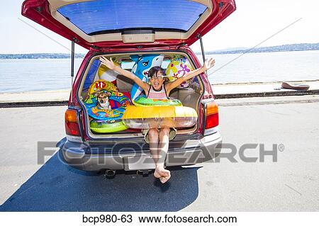 Child poses with his dog in the open trunk of a car full of beach toys and floaties View Large Photo Image Stock Image - Child poses with his dog in the open trunk of a car full of beach toys and floaties. Fotosearch
