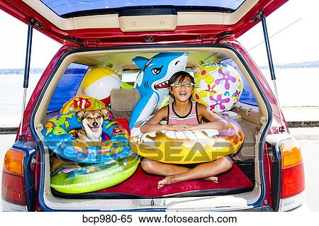 Child poses with his dog in the open trunk of a car full of beach toys and floaties View Large Photo Image Stock Photography - Child poses with his dog in the open trunk of a car full of beach toys and floaties. Fotosearch