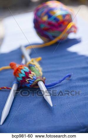 Stock Image - Colorful knitting on a blue cushion. Fotosearch