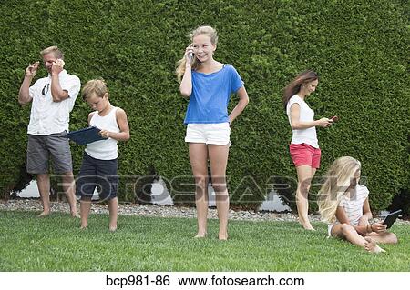 Family of five all using technology outdoors View Large Photo Image Stock Photograph - Family of five all using technology outdoors. Fotosearch