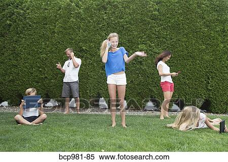 Family of five all using technology outdoors View Large Photo Image Stock Photography - Family of five all using technology outdoors. Fotosearch