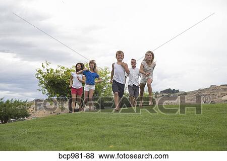 Stock Photo - Family of five running up a grassy hill. Fotosearch