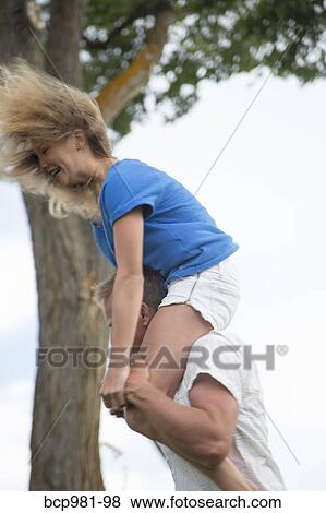 Father with his tween daughter on his shoulders on a windy day View Large Photo Image Stock Photo - Father with his tween daughter on his shoulders on a windy day. Fotosearch