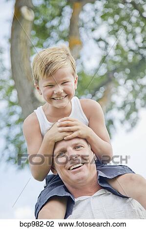 Father with his young son on his shoulders View Large Photo Image Stock Image - Father with his young son on his shoulders. Fotosearch