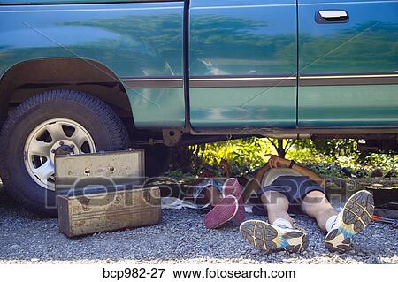 Stock Photo - "Man and a boy lying under a vehicle with a toolbox, doing repairs". Fotosearch