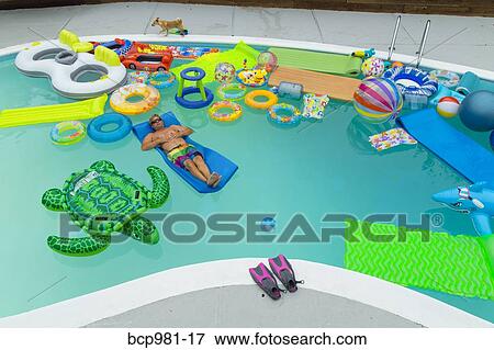 Man floats in a pool full of inflatable toys View Large Photo Image Stock Photo - Man floats in a pool full of inflatable toys. Fotosearch