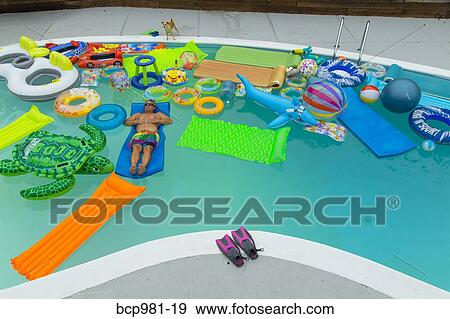 Man floats in a pool full of inflatable toys View Large Photo Image Stock Photo - Man floats in a pool full of inflatable toys. Fotosearch