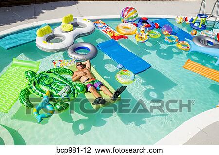 Man wearing flippers floats in a pool full of inflatable toys View Large Photo Image Stock Image - Man wearing flippers floats in a pool full of inflatable toys. Fotosearch