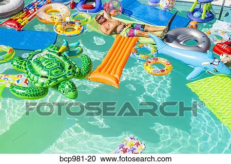 Man wearing flippers floats in a pool full of inflatable toys View Large Photo Image Stock Image - Man wearing flippers floats in a pool full of inflatable toys. Fotosearch