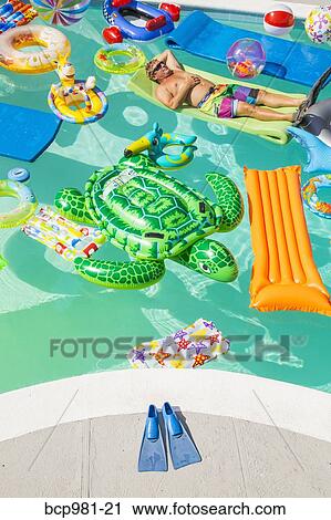 Man wearing flippers floats in a pool full of inflatable toys View Large Photo Image Stock Image - Man wearing flippers floats in a pool full of inflatable toys. Fotosearch