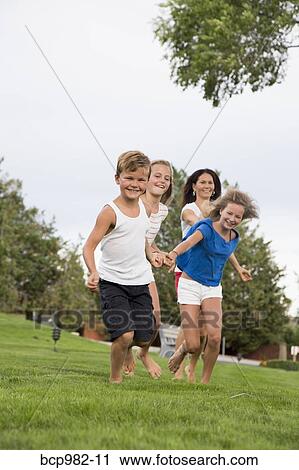 Mother running on grass with her three children View Large Photo Image Stock Image - Mother running on grass with her three children. Fotosearch