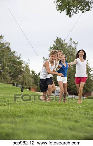 Mother running on grass with her three children View Large Photo Image Stock Image - Mother running on grass with her three children. Fotosearch