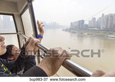 Stock Photo - "Passengers ride in a cable car over the Yangtze river, Chonqing, China". Fotosearch