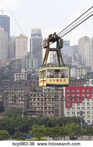 Stock Photo - "Passengers ride in a cable car with a view of Chonqing, China". Fotosearch
