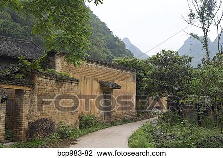 Stock Image - Path by brick buildings in a rural Chinese village. Fotosearch