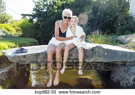 Portrait of a grandmother and granddaughter sitting on a stone bridge over a small creek View Large Photo Image Stock Image - Portrait of a grandmother and granddaughter sitting on a stone bridge over a small creek. Fotosearch