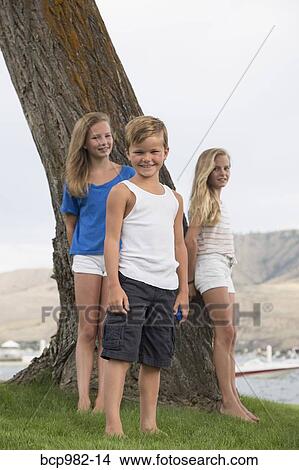 Portrait of three children by a tree near a lake View Large Photo Image Picture - Portrait of three children by a tree near a lake. Fotosearch