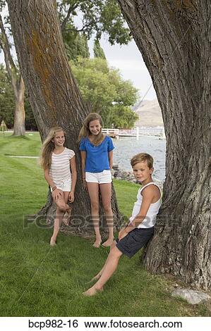 Portrait of three children by a tree near a lake View Large Photo Image Stock Photograph - Portrait of three children by a tree near a lake. Fotosearch