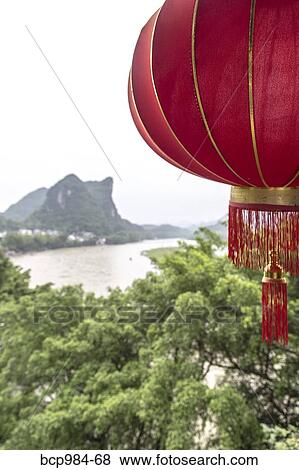"Red lantern hanging in front of a view of the Karst mountains and Li River, Yangshuo, China" View Large Photo Image Stock Photo - "Red lantern hanging in front of a view of the Karst mountains and Li River, Yangshuo, China". Fotosearch