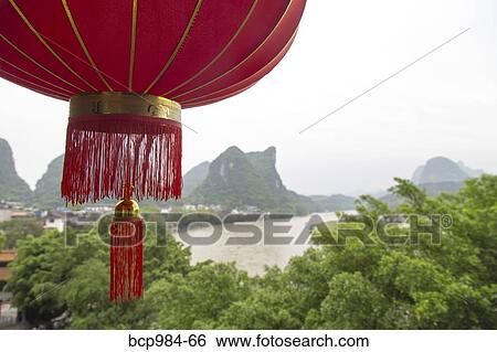 Stock Photograph - "Red lantern hanging in front of a view of the Karst mountains and Li River, Yangshuo, China". Fotosearch
