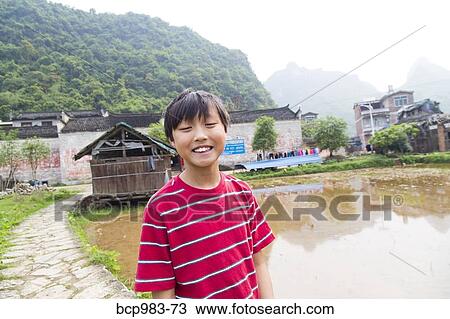 Stock Image - "Smiling boy near a rice paddy in a rural village, Yangshuo, China". Fotosearch