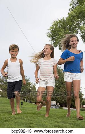 Three children running on grass View Large Photo Image Stock Image - Three children running on grass. Fotosearch
