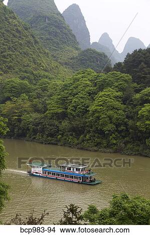 "Tour boat travelling the Li River between Guilin and Yangshuo, China" View Large Photo Image Picture - "Tour boat travelling the Li River between Guilin and Yangshuo, China". Fotosearch