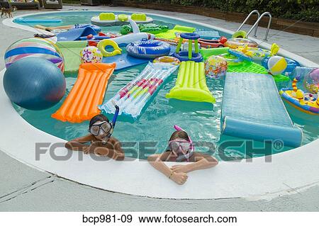 Stock Photo - Two children wearing scuba masks and snorkels swim in a pool full of inflatable toys. Fotosearch
