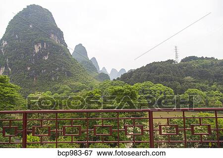 Stock Photo - "View of mountains beyond a fenced patio, Yangshuo, China". Fotosearch