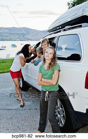 Stock Image - Woman kissing a man through a car window in front of their kids. Fotosearch