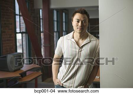 A casually-dressed man leaning against doorway in loft-style office. View Large Photo Image Picture - A casually-dressed man leaning against doorway in loft-style office.. Fotosearch