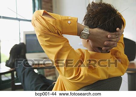 A man leaning back at his desk and thinking. View Large Photo Image Picture - A man leaning back at his desk and thinking.. Fotosearch