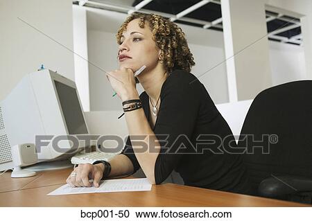A young woman working at her desk. View Large Photo Image Stock Image - A young woman working at her desk.. Fotosearch
