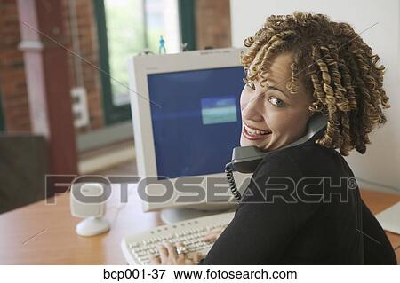 A young woman working at her desk. View Large Photo Image Stock Photo - A young woman working at her desk.. Fotosearch