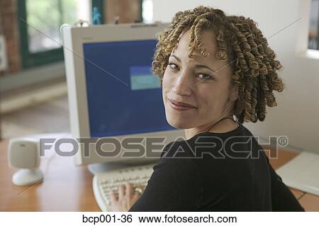 A young woman working at her desk. View Large Photo Image Stock Photograph - A young woman working at her desk.. Fotosearch