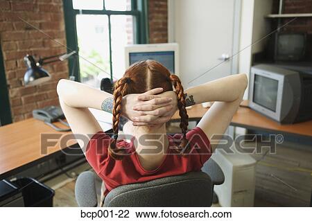 Red-haired woman leaning back at her office desk. View Large Photo Image Stock Image - Red-haired woman leaning back at her office desk.. Fotosearch