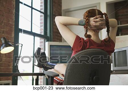 Red-haired woman leaning back at her office desk. View Large Photo Image Stock Image - Red-haired woman leaning back at her office desk.. Fotosearch