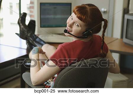 Red-headed woman talking on a headset phone with feet on desk. View Large Photo Image Stock Photography - Red-headed woman talking on a headset phone with feet on desk.. Fotosearch