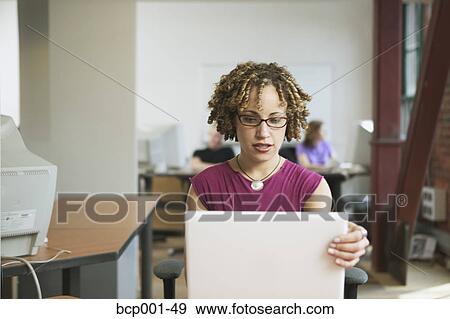 Seated at her desk, a multi-ethnic woman, 20s, works at computer. View Large Photo Image Stock Photo - Seated at her desk, a multi-ethnic woman, 20s, works at computer.. Fotosearch