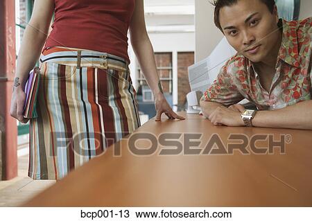 Two casually-dressed office workers at a desk. View Large Photo Image Stock Image - Two casually-dressed office workers at a desk.. Fotosearch