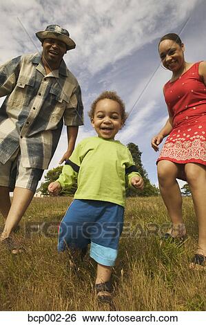 Stock Photograph - A couple playing with their son in a grassy field. . Fotosearch