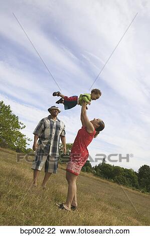 A couple playing with their son in grassy field. View Large Photo Image Stock Image - A couple playing with their son in grassy field. . Fotosearch